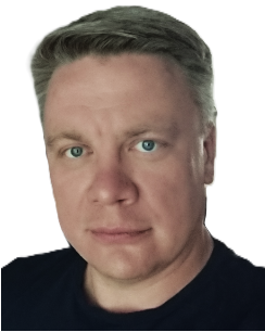 Harmaahiuksinen mies katsoo kameraan, neutraali ilme, tummansininen paita, valkoinen tausta.
